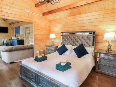 A bedroom with a bed and bedside tables with lamps next to a living area and kitchenette at Drumrane Lodge in Dungiven Londonderry