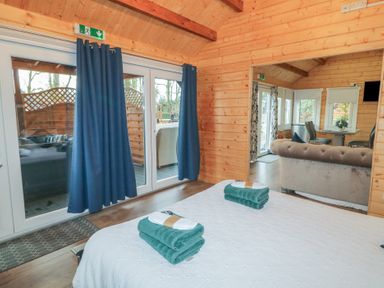 A bedroom with a bed and towels overlooking a living room with a sofa and dining table at Drumrane Lodge in Dungiven Londonderry