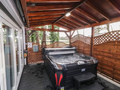 A covered outdoor area with a hot tub and wooden lattice fencing at Drumrane Lodge in Dungiven Londonderry