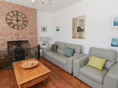 A living room with a clock and fireplace at Brynmorfa in Llandysul