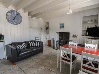 A living room with a sofa, dining table, and fireplace at Brynmorfa in Llandysul