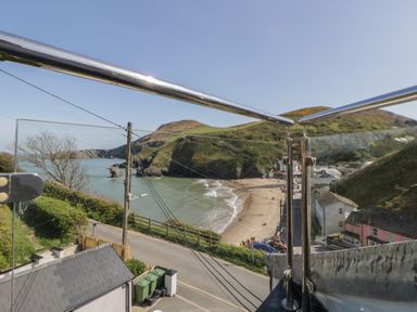A view of a beach and hills from a balcony at Brynmorfa in Llandysul