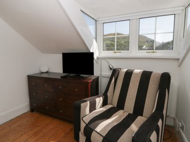 A bedroom with a chair and a television at Brynmorfa in Llandysul
