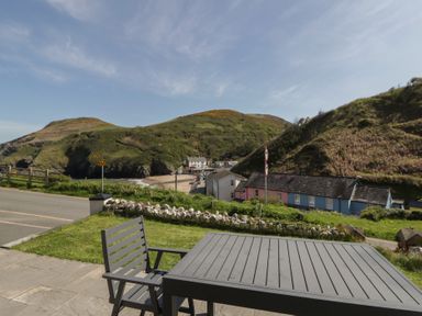 A table and chair with a view of hills and houses at Brynmorfa Llandysul