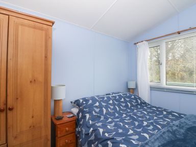 A bedroom with a bed, wardrobe, lamp, and window at Scarba in Oban