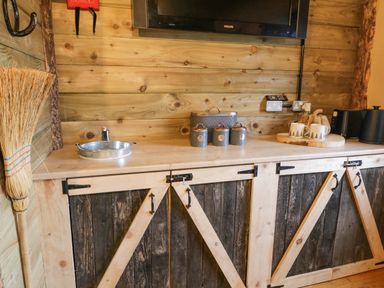 A kitchen counter with metal canisters mugs toaster and a broom at Bear Claw Lodge in Castlerock