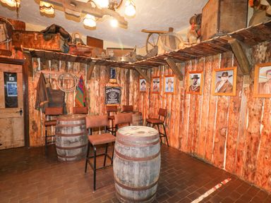 A rustic room with wooden barrel tables and chairs and portraits on wood-paneled walls at Bear Claw Lodge in Castlerock