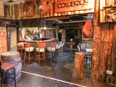 A wooden bar area with stools a fireplace and cowboy decor at Bear Claw Lodge in Castlerock