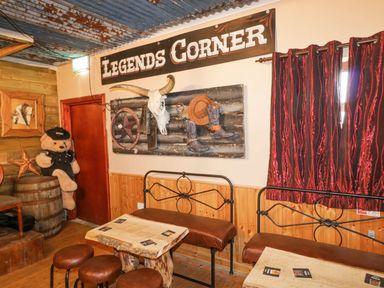 An indoor seating area with leather benches wooden tables a large teddy bear a bull skull and cowboy decor at Bear Claw Lodge in Castlerock