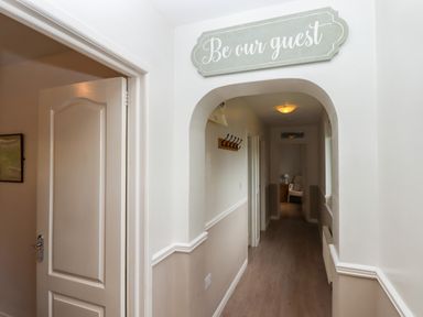 A hallway with an open door a coat rack and a sign reading Be our guest at Castle View Lodge in Ilfracombe