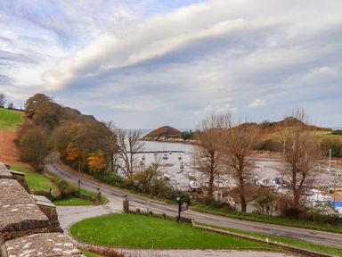 A coastal road with parked boats and hills in the background at Castle View Lodge in Ilfracombe