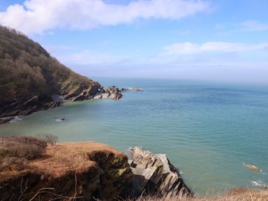 A coastal landscape with rocky cliffs and calm sea at Castle View Lodge in Ilfracombe