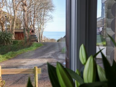 A view of a road and water from a window at Castle View Lodge in Ilfracombe