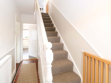 A staircase and hallway leading to a door at Highland House in Sheringham
