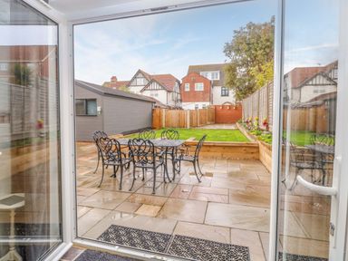 A garden with a patio area and a dining table at Highland House in Sheringham