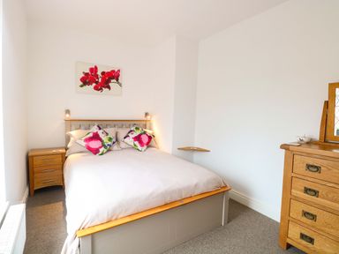 A bedroom with a bed and nightstand at Highland House in Sheringham