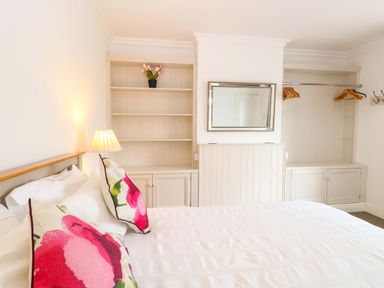 A bedroom with a bed and shelves at Highland House Sheringham