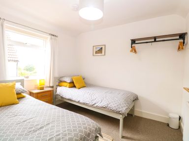 A bedroom with two beds and a window at Highland House in Sheringham