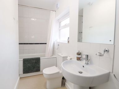 A bathroom with a bathtub, toilet, and sink at Highland House in Sheringham