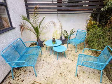 An outdoor seating area with three blue chairs a blue bench two blue tables plants and decorative stars at Riverwash Cottage in Dwygyfylchi