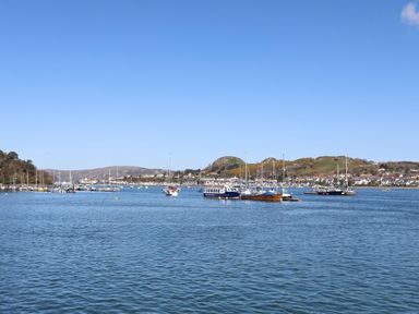 A harbor with boats on the water and houses on the hills in the background at Riverwash Cottage in Dwygyfylchi