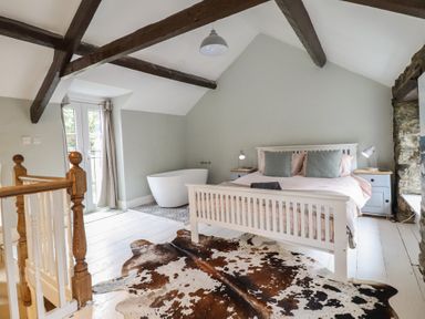 A bedroom with a bed and bathtub at Riverwash Cottage in Dwygyfylchi