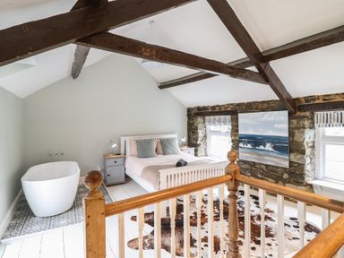 A bedroom with a bed and a bathtub at Riverwash Cottage Dwygyfylchi