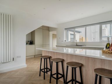 A kitchen with a large island and bar stools at Seaddler Trearddur Bay