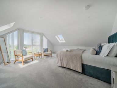 A bedroom with a bed and chairs at Seaddler in Trearddur Bay