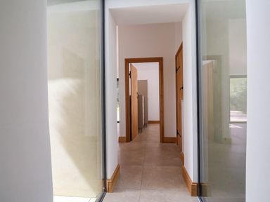 A hallway with tiled floor and wooden door frames visible through glass walls at Upper Cottage in Rocombe near Uplyme