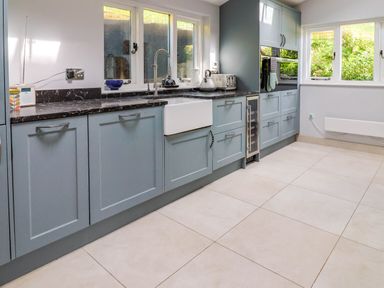 A kitchen with blue cabinets black countertop white farmhouse sink built in oven and appliances at Upper Cottage in Rocombe near Uplyme