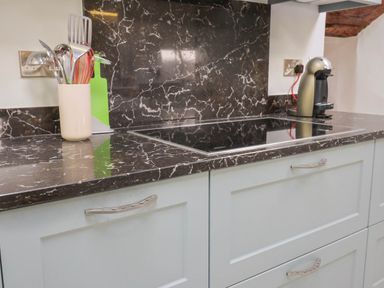 A kitchen countertop with a stove a utensil holder and a coffee machine at Upper Cottage Rocombe near Uplyme
