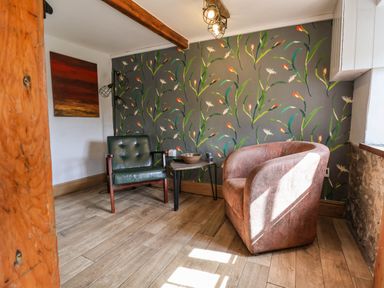 A small seating area with two chairs a small table and floral wallpaper at Upper Cottage in Rocombe near Uplyme