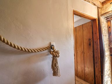A wall with a thick rope tied and attached near a wooden doorway at Upper Cottage in Rocombe near Uplyme