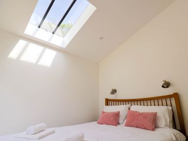 A bedroom with a skylight window two pink pillows and white rolled towels at Upper Cottage in Rocombe near Uplyme