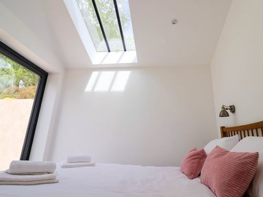 A bedroom with a bed towels on top and pink pillows with a skylight window at Upper Cottage in Rocombe near Uplyme
