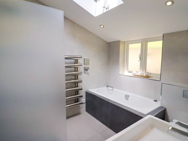 A bathroom with a bathtub radiator window and sink at Upper Cottage in Rocombe near Uplyme