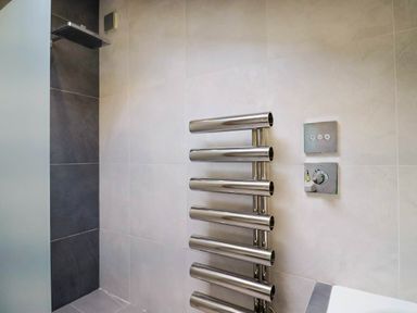 A modern bathroom with a stainless steel towel radiator shower controls and a rain shower head at Upper Cottage in Rocombe near Uplyme