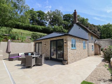 An outdoor seating area with a table and chairs at Upper Cottage Rocombe near Uplyme