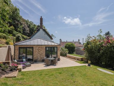 A garden with a patio, table and chairs at Upper Cottage in Rocombe near Uplyme
