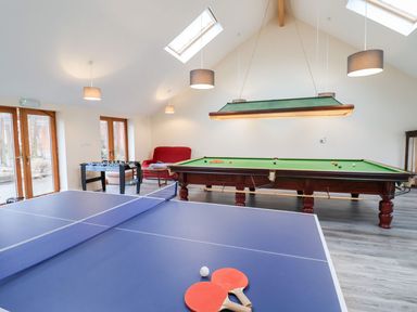 A game room with a ping pong table foosball table snooker table and a red couch at Mill Cottage in Aylesbeare