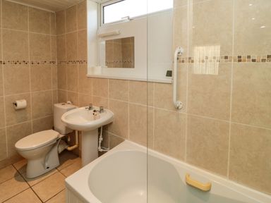 A bathroom with a toilet sink bathtub and tiled walls at Stable Cottage in Cottonshopeburnfoot near Otterburn