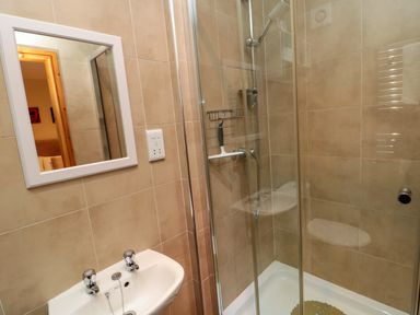 A bathroom with a sink a mirror and a glass-enclosed shower at Fir Tree Cottage in Cottonshopeburnfoot near Otterburn