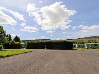 An outdoor view of caravans and grass at Fir Tree Cottage Cottonshopeburnfoot near Otterburn