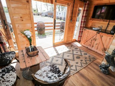A wooden cabin interior with patterned rug table two chairs and a wooden cabinet with a sink at Whiskey Creek Cabin in Castlerock