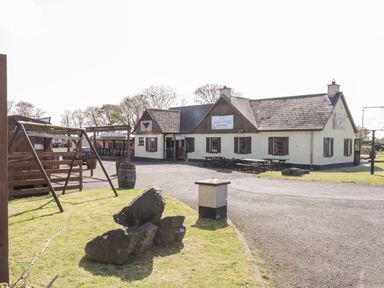 An outdoor area with a building labeled The Blazin Saddle Saloon a swing set picnic tables barrels and rocks