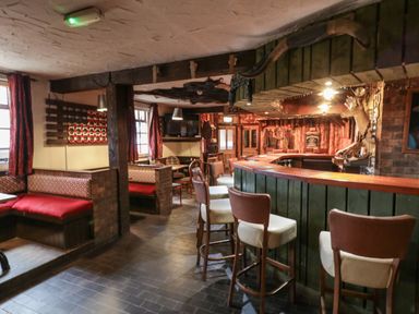 An interior view of a bar with high stools and seating booths at Whiskey Creek Cabin in Castlerock