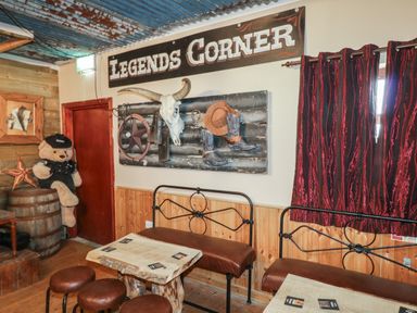 A room with western decor including a bull skull hat boots and a sign reading Legends Corner at Whiskey Creek Cabin in Castlerock