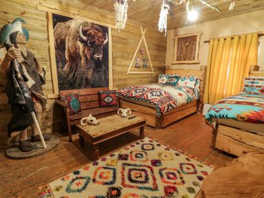 A bedroom with two beds wooden walls a wooden bench a coffee table and a statue at Apache Falls Lodge in Castlerock