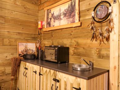 A kitchen counter with a small oven radio and decorations on wooden walls at Apache Falls Lodge in Castlerock